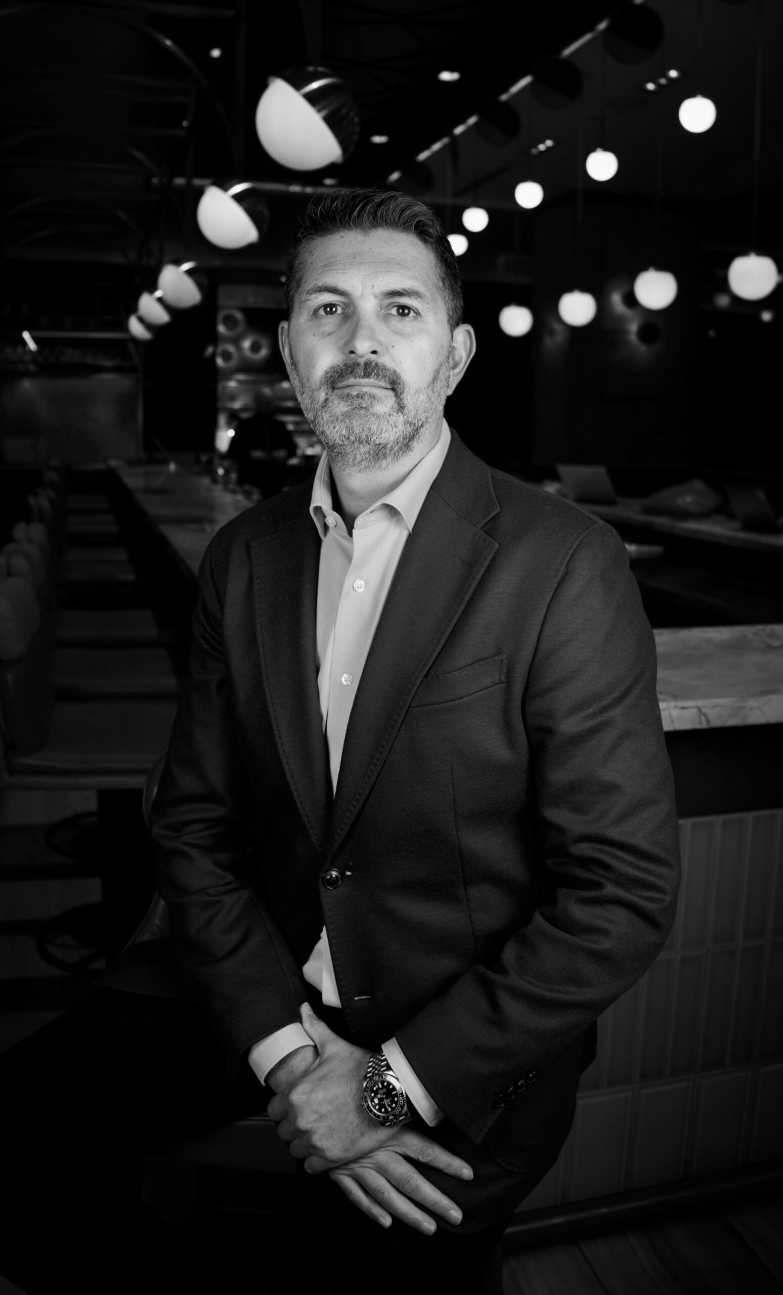 Yannick Bigourdan, founder of KLTY Hospitality Consulting — monochrome editorial portrait in a hospitality setting