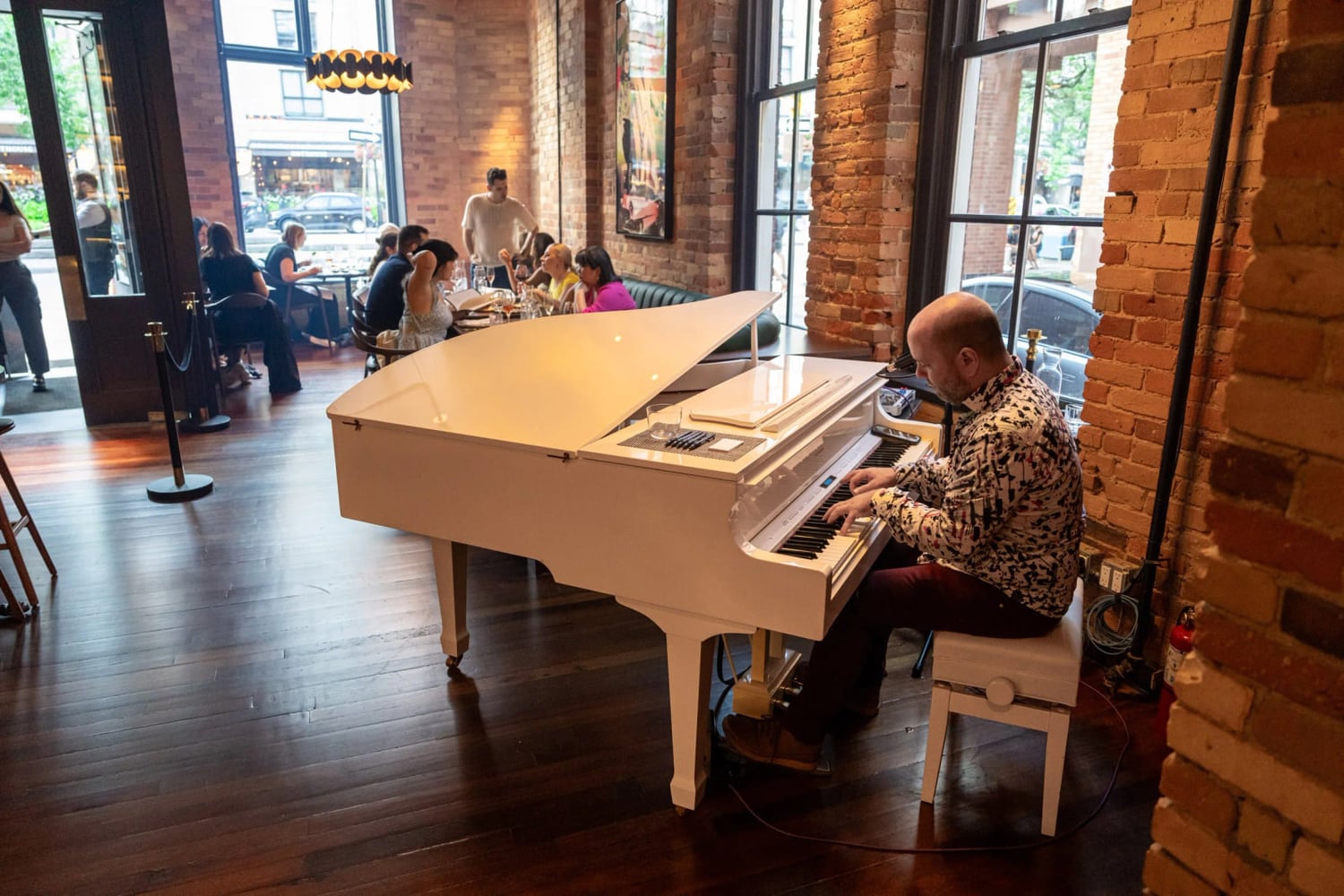 The Berczy Tavern in Toronto's St Lawrence district — a pianist at a white grand piano in the dining room, brick walls and tall windows behind, guests at banquettes